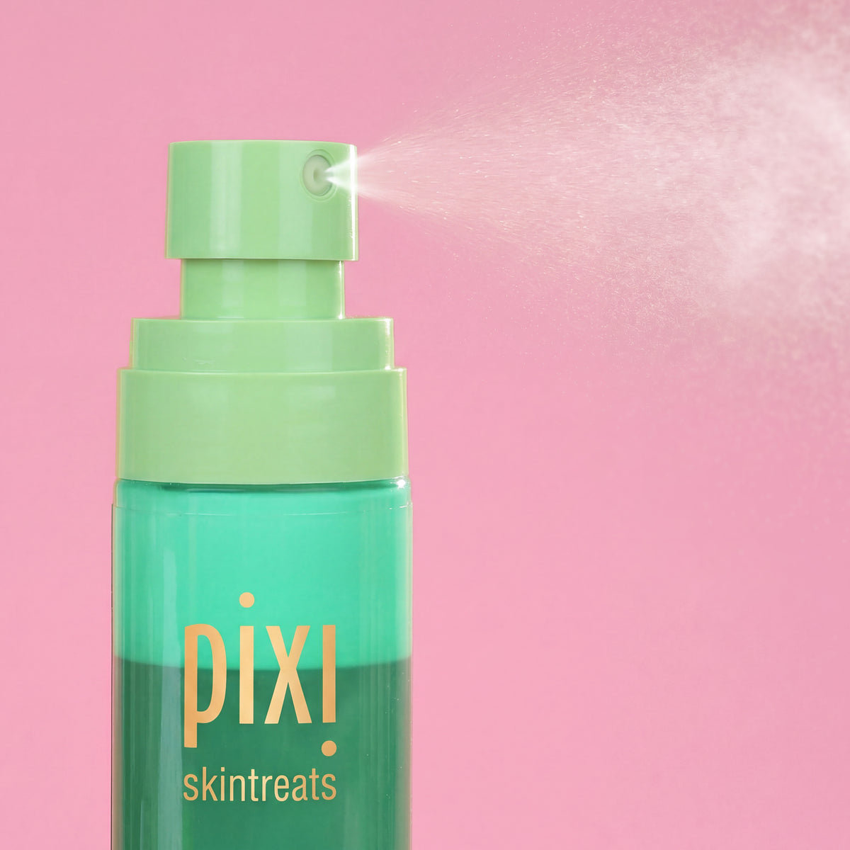 Pixi Skintreats Antioxidant Mist bottle with a light green pump spraying a fine mist against a solid pink background.